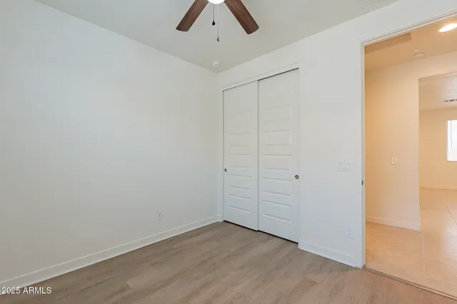 an empty room with ceiling fan and window
