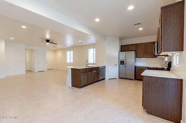 a large kitchen with a large counter top a sink stainless steel appliances and cabinets