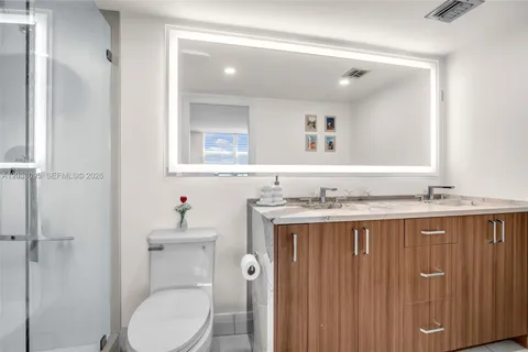 a bathroom with a granite countertop toilet sink and mirror