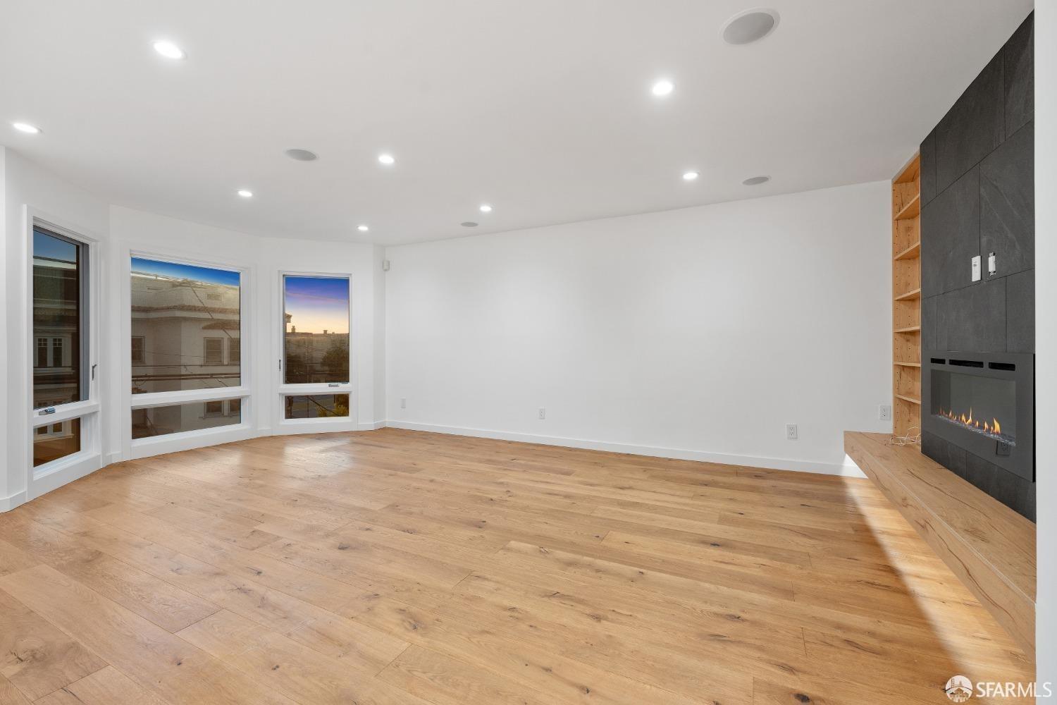 174-172 18th Avenue, Unit 172 San Francisco, CA 94121 - Photo 9 of 37 a view of an empty room with wooden floor and a kitchen