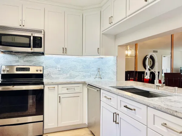 a kitchen with granite countertop white cabinets and stainless steel appliances