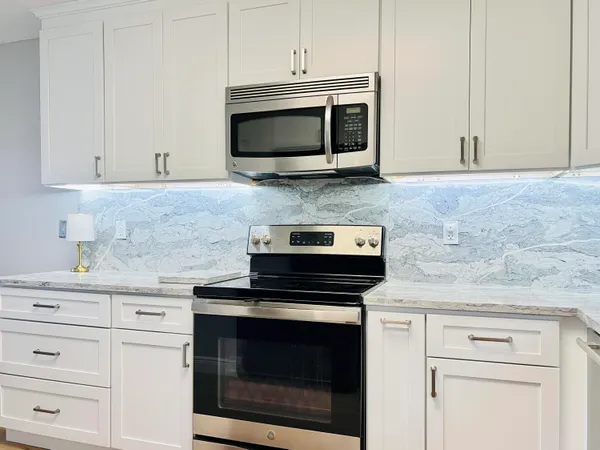 a kitchen with granite countertop white cabinets and stainless steel appliances