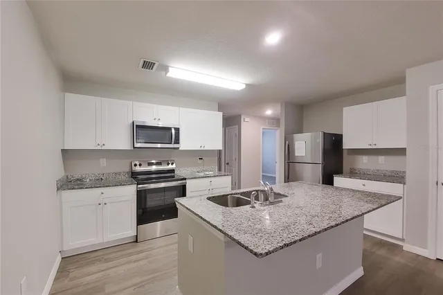 a kitchen with stainless steel appliances granite countertop a sink stove and refrigerator