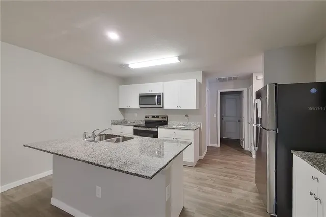 a kitchen with stainless steel appliances granite countertop a sink stove and refrigerator