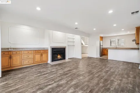 a view of empty room with kitchen and fireplace