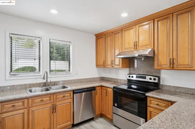 a kitchen with granite countertop a sink stainless steel appliances and cabinets