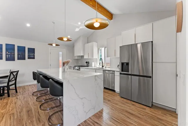 a kitchen with kitchen island a counter top space a sink a refrigerator and wooden floor