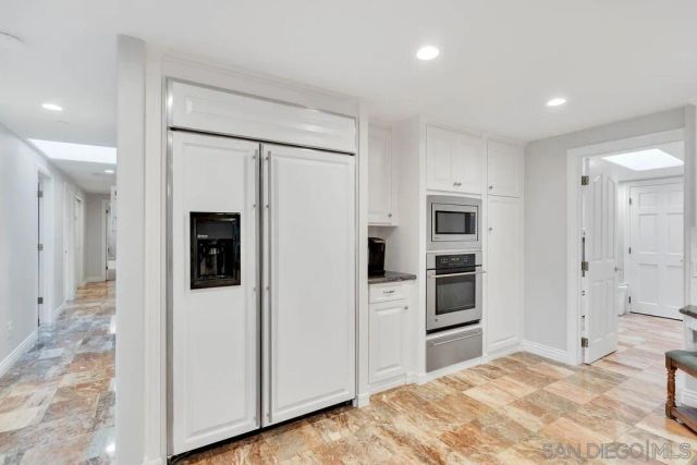 a view of a kitchen with refrigerator and white cabinets