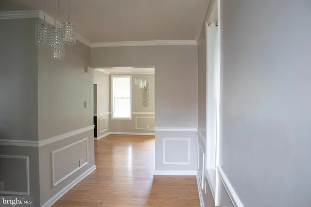 a view of hallway with window and wooden floor