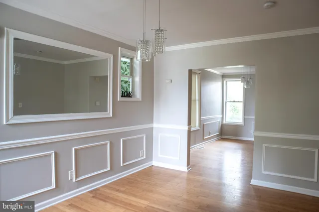 a view of a hallway with wooden floor and a chandelier