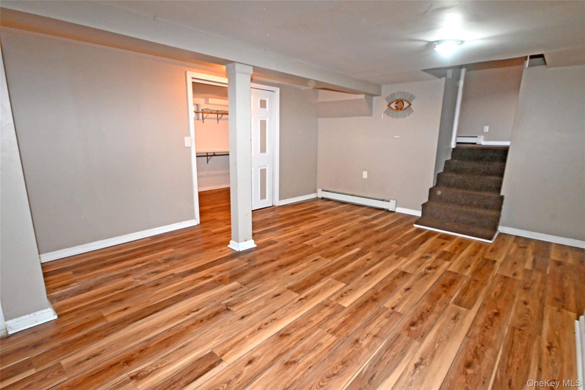 89 Osborne Road West Hempstead, NY 11552 - Photo 47 of 50 Finished basement with a baseboard radiator, light wood finished floors, and stairs