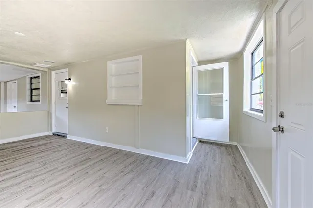 an empty room with wooden floor and windows