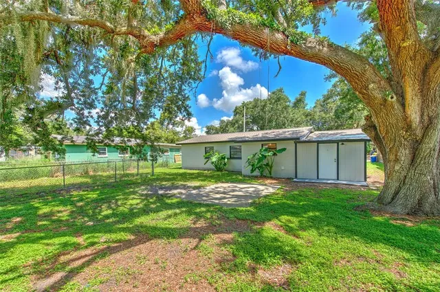 a view of an house with backyard and a tree