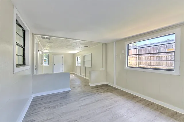 a view of empty room with wooden floor and fan