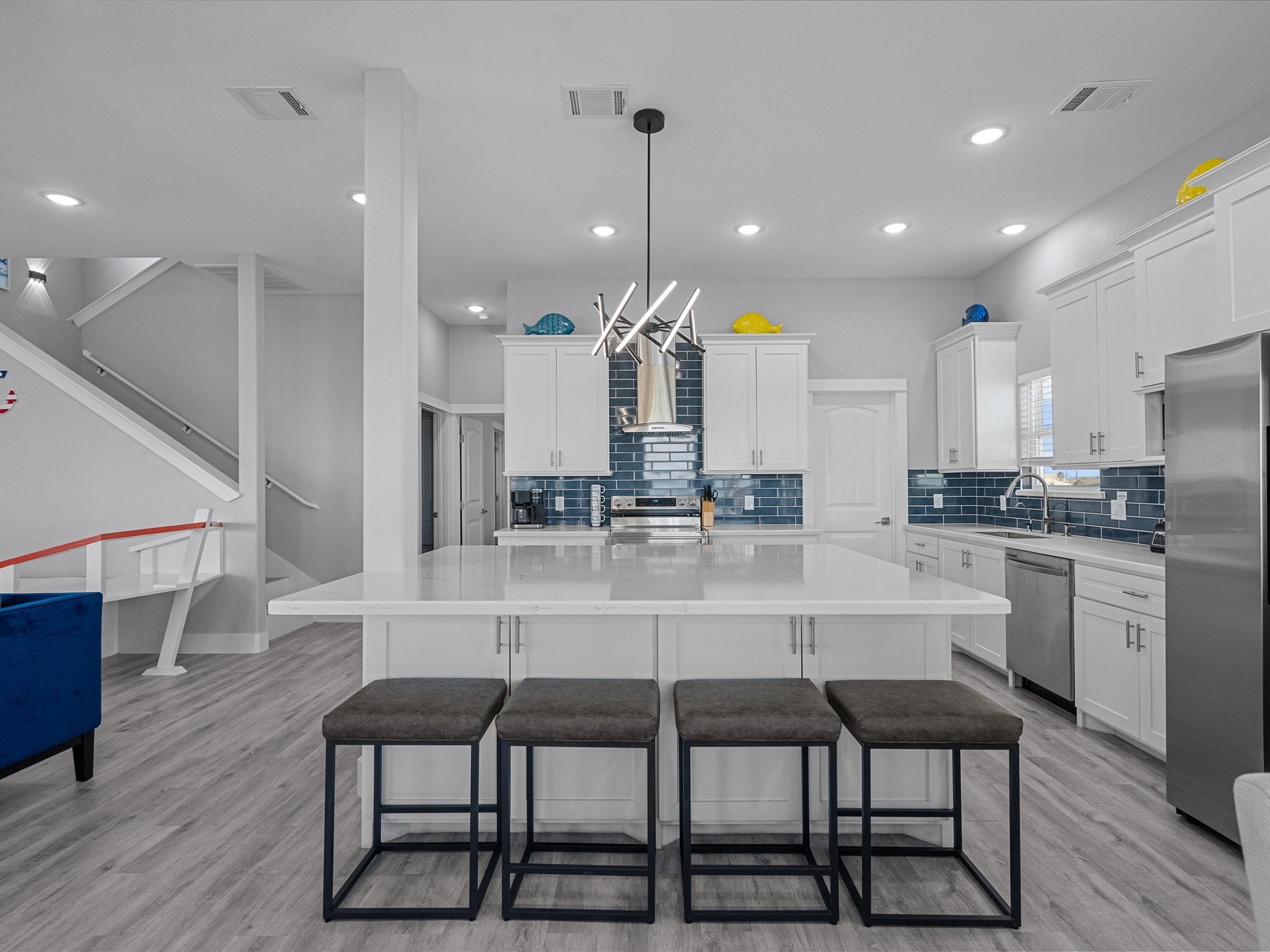 718 Beach Drive Surfside Beach, TX 77541 - Photo 14 of 49 Discover this modern open-concept living space featuring a bright kitchen with a large island, sleek white cabinetry, and chic lighting. Enjoy the spacious living room with a fireplace, expansive windows for natural light, and a cozy dining area.