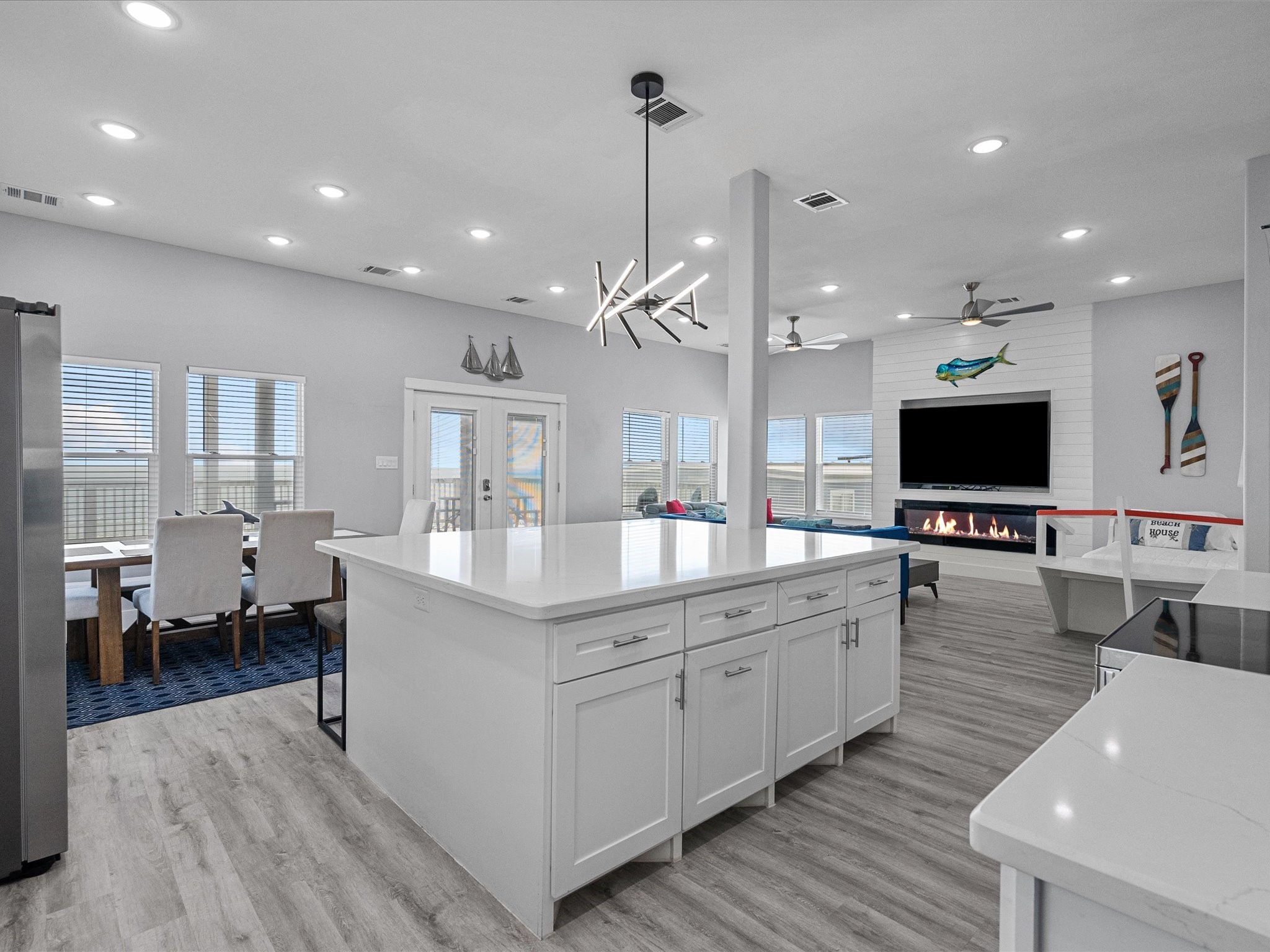 718 Beach Drive Surfside Beach, TX 77541 - Photo 17 of 49 This modern open-concept space features sleek flooring, a cozy fireplace with a mounted TV, and an abundance of natural light through large windows. The stylish seating area and contemporary open staircase complete the inviting atmosphere.