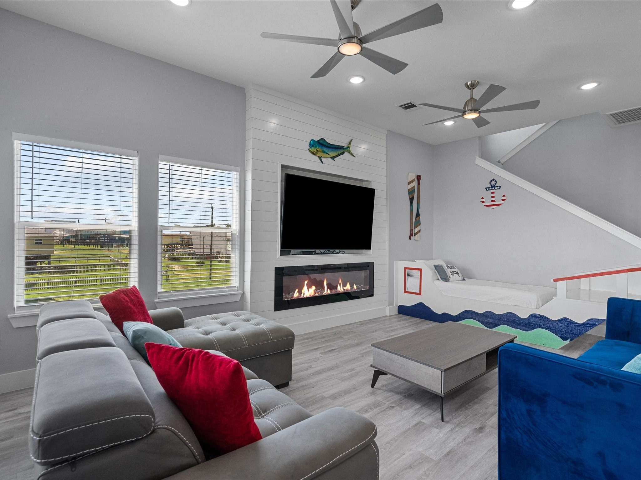 718 Beach Drive Surfside Beach, TX 77541 - Photo 21 of 49 This inviting bedroom features a sleek gray color palette, modern decor, and stylish side tables. Natural and recessed lighting illuminate the elegant wood flooring, while a ceiling fan adds comfort.