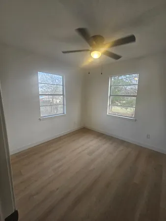 an empty room with windows and fan