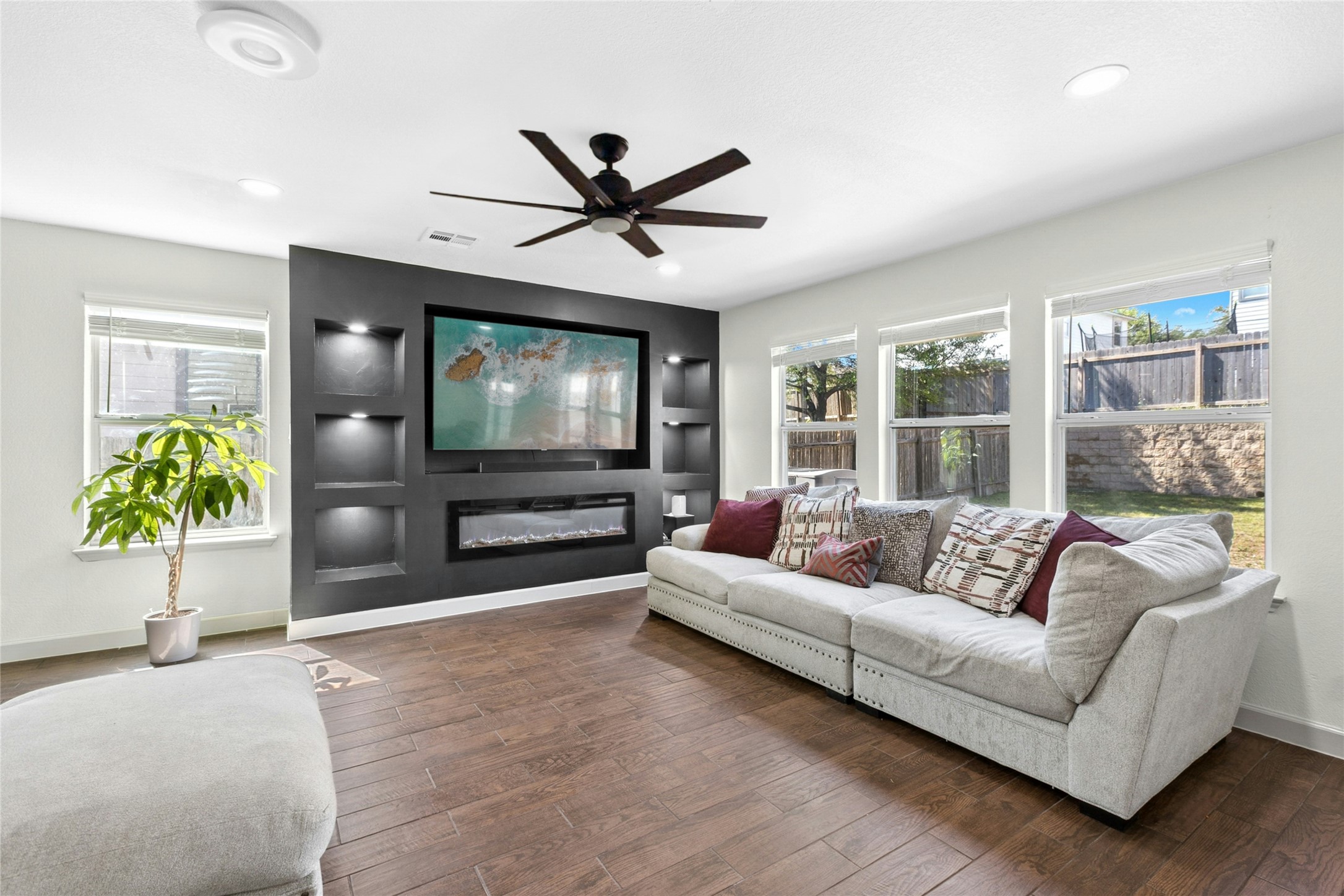 Living room with hardwood / wood-style flooring, a glass covered fireplace, and ceiling fan