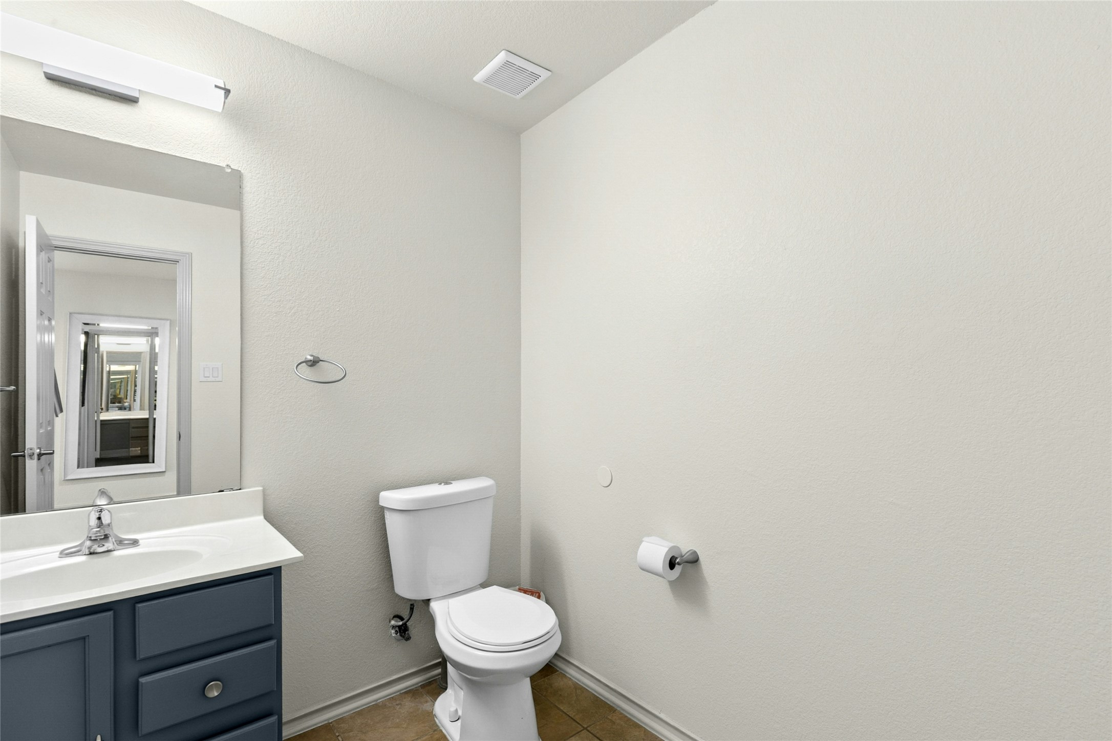 245 Myrtle Street Kyle, TX 78640 - Photo 11 of 24 Half bath.
Bathroom featuring vanity, dark tile patterned flooring, and a textured wall