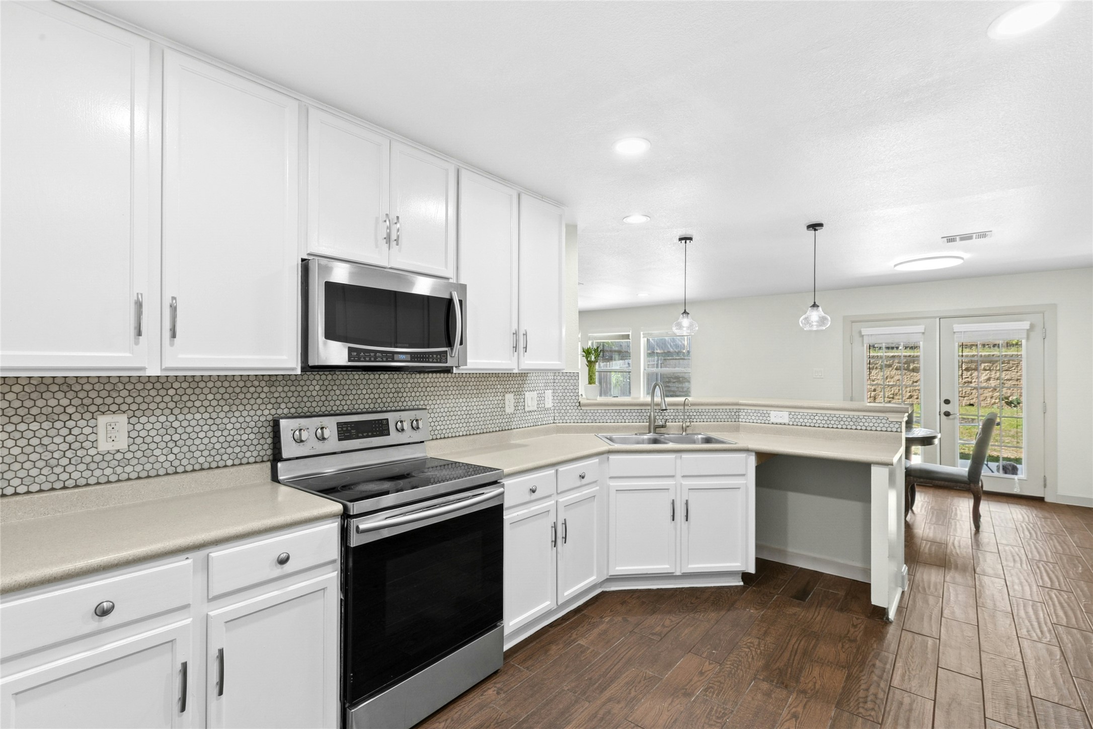245 Myrtle Street Kyle, TX 78640 - Photo 8 of 24 Kitchen featuring stainless steel appliances, white cabinets, light countertops, a peninsula, and dark wood-type flooring
