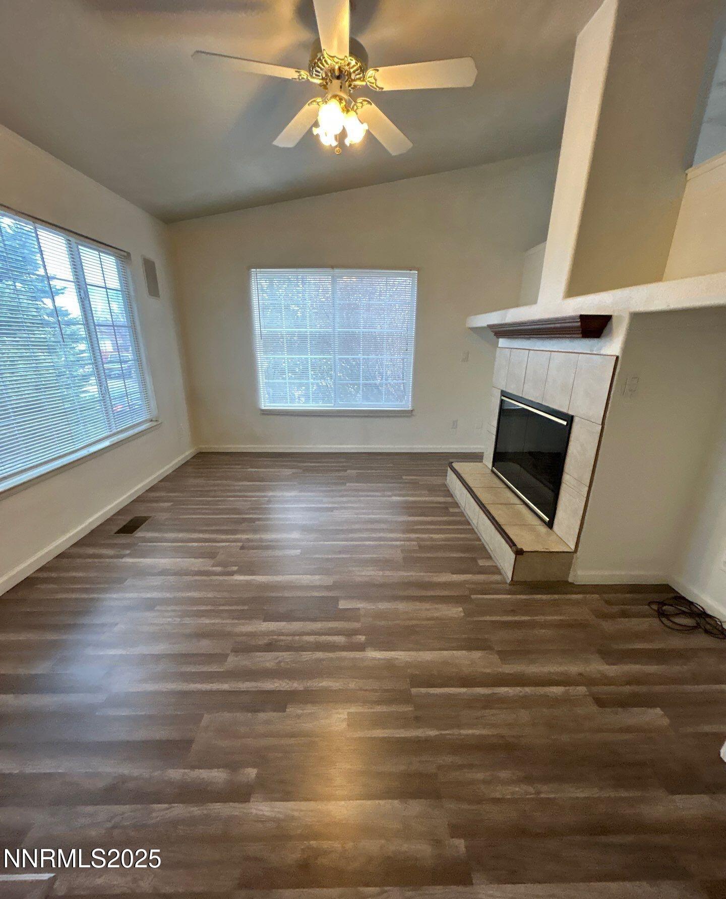 7470 Rodin Court Sun Valley, NV 89433 - Photo 3 of 23 a view of an empty room with wooden floor fireplace and a window