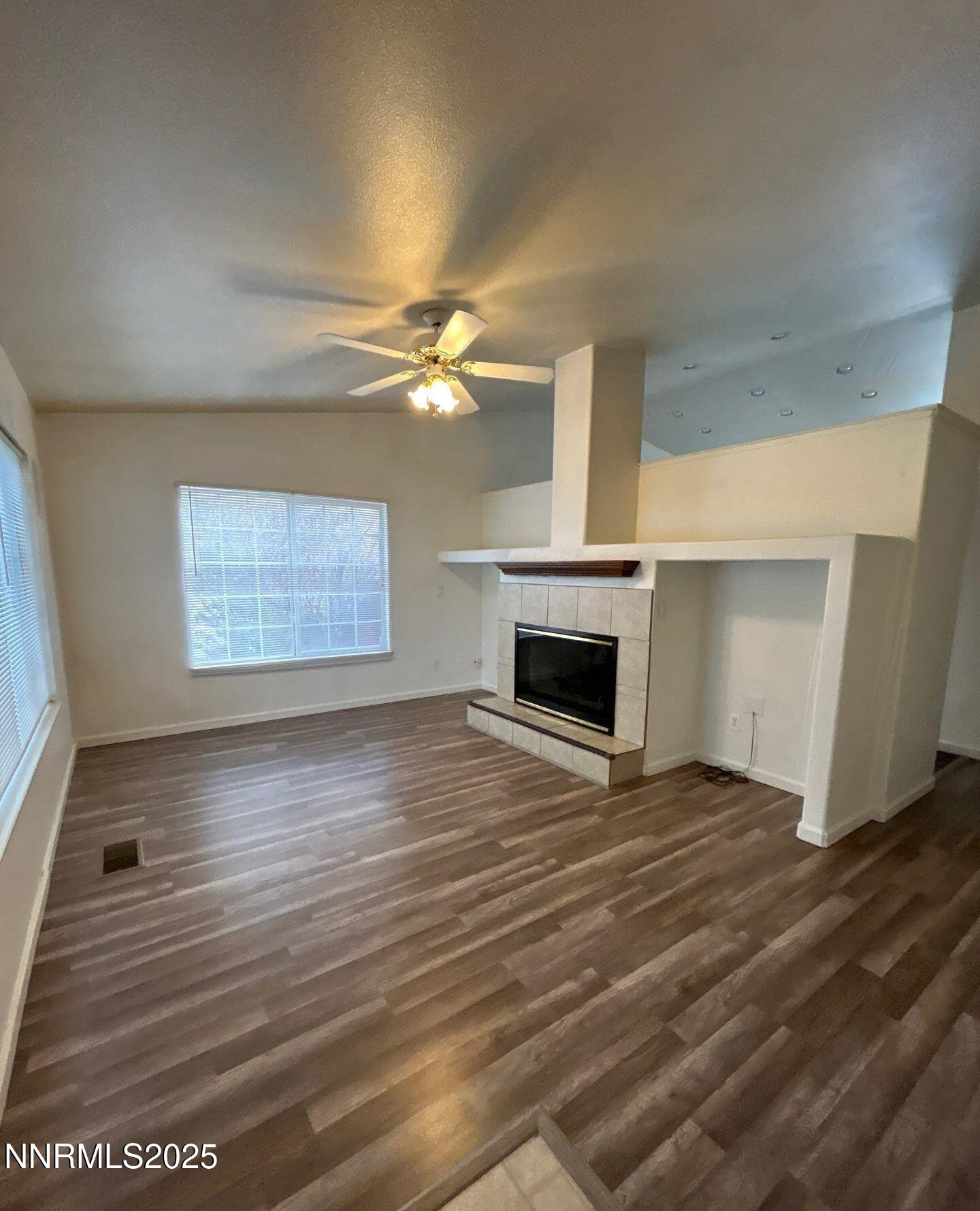 7470 Rodin Court Sun Valley, NV 89433 - Photo 4 of 23 an empty room with wooden floor fireplace and windows