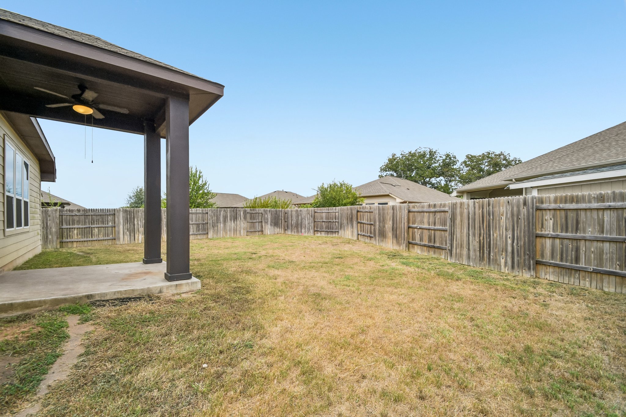 280 Rimrock Court Bastrop, TX 78602 - Photo 32 of 34 A spacious lawn enclosed by a wooden privacy fence is accessed from a covered concrete patio.