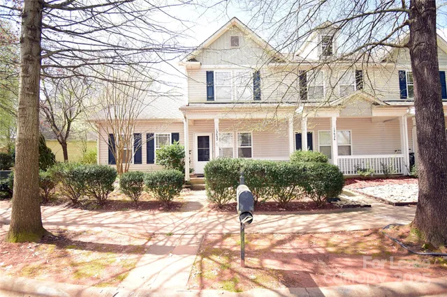 a front view of a house with a yard covered with snow and plants
