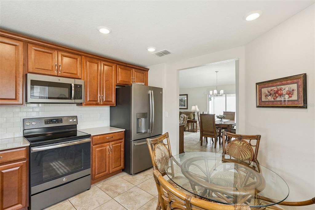 3342 Raleigh Drive Winter Haven, FL 33884 - Photo 9 of 50 a kitchen with stainless steel appliances granite countertop a refrigerator a stove a sink a dining table and chairs