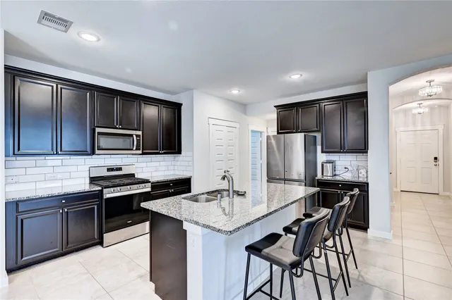 a kitchen with stainless steel appliances kitchen island granite countertop a stove refrigerator and microwave