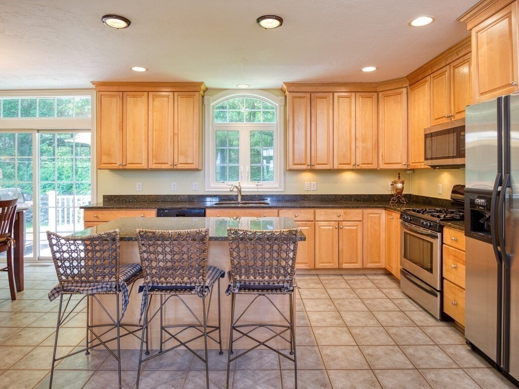 126 Walnut Street Shrewsbury, MA 01545 - Photo 12 of 41 a kitchen with stainless steel appliances granite countertop a stove a sink dishwasher a dining table and chairs with wooden floor