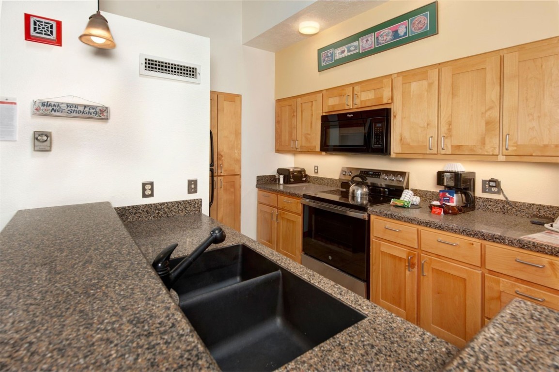 21630 Highway 6, Unit 2150 Keystone, CO 80435 - Photo 9 of 46 a kitchen with stainless steel appliances granite countertop a sink dishwasher stove and microwave with wooden floor