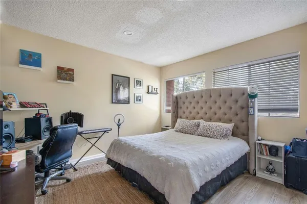 a bedroom with a bed a desk and chair with wooden floor