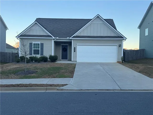 a front view of a house with garage and plants