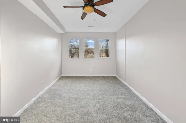 an empty room with a ceiling fan and window