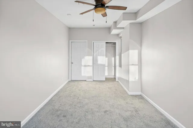 an empty room with chandelier fan and windows