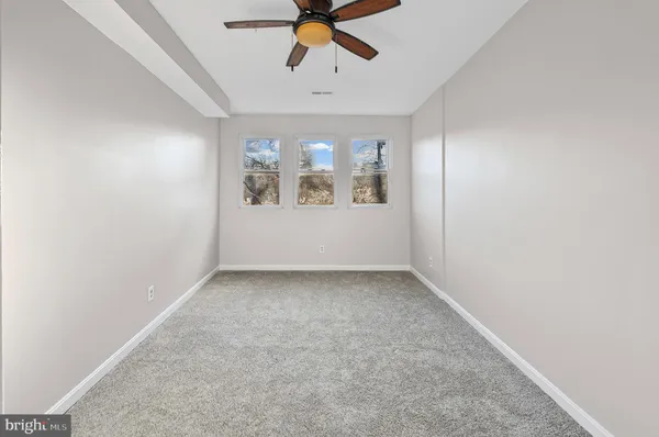 an empty room with a ceiling fan and window