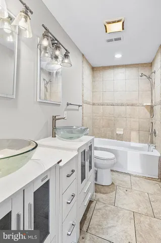 a bathroom with a granite countertop sink a toilet and bathtub