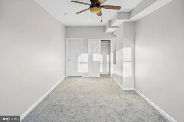 an empty room with chandelier fan and windows