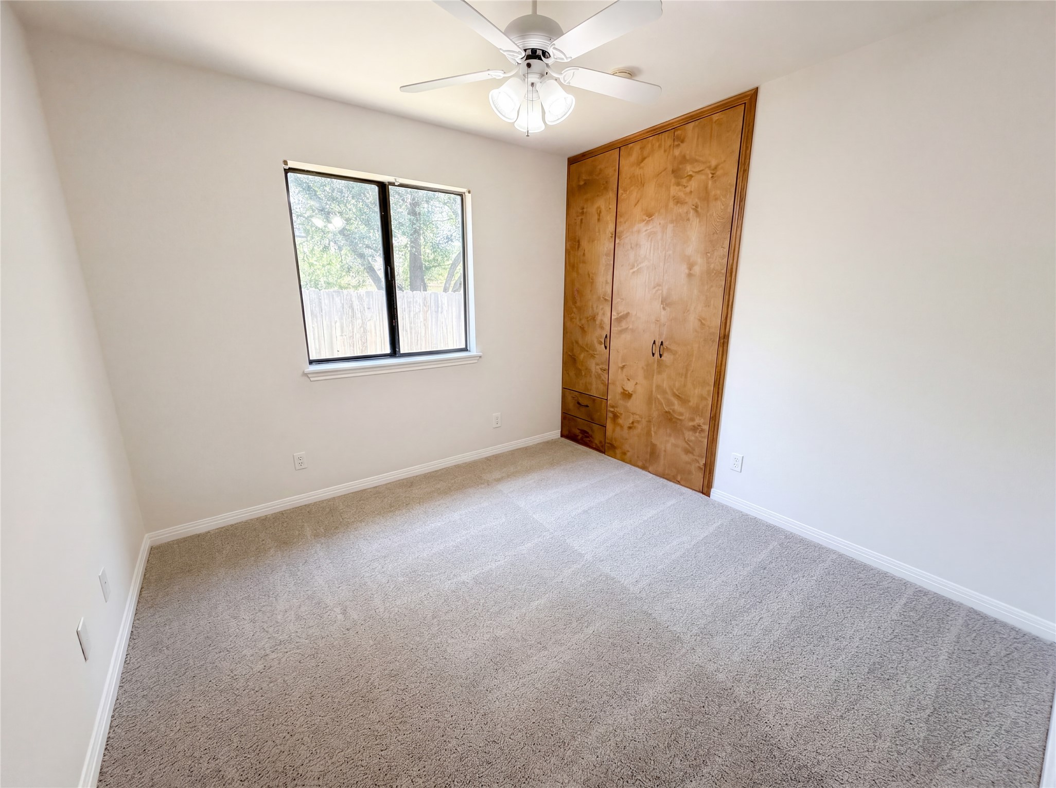 1111 North Riviera Circle Cedar Park, TX 78613 - Photo 9 of 17 Carpeted interior space featuring a ceiling fan with light fixture, a window with a white sill, and a built-in wooden wardrobe with integrated drawers