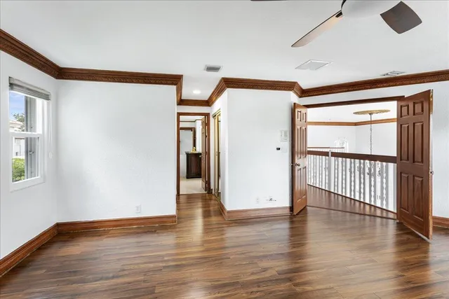 a view of an empty room with wooden floor and a window