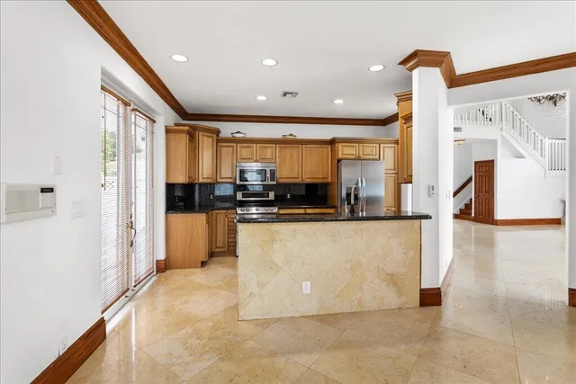 a living room with stainless steel appliances furniture a refrigerator and a kitchen view