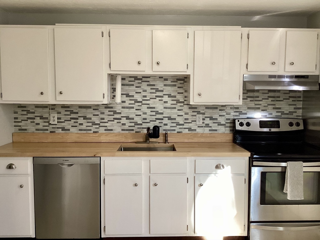 300 Falmouth Road, Unit 6B Mashpee, MA 02649 - Photo 4 of 27 a kitchen with granite countertop white cabinets and stainless steel appliances