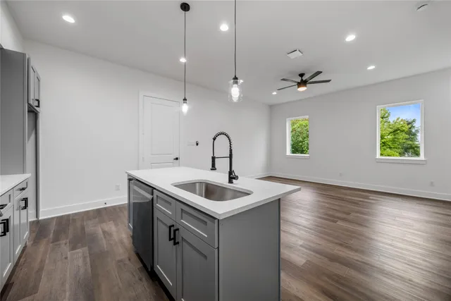 a kitchen that has a sink and a stove with wooden floor