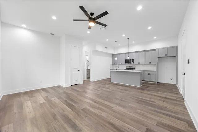 a view of a kitchen with kitchen island a sink wooden floor and a refrigerator