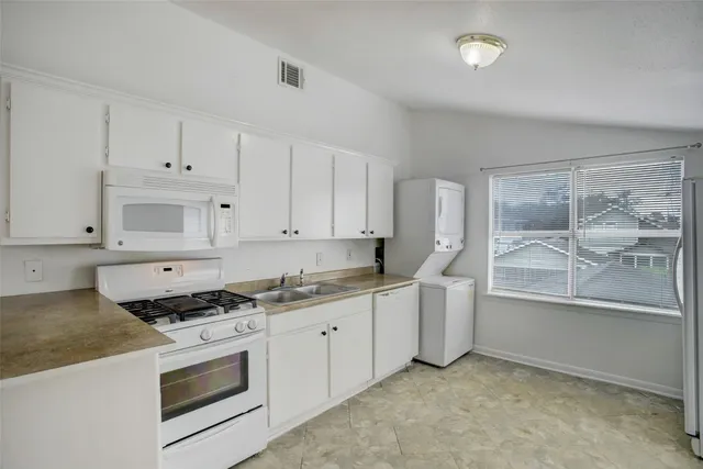 a kitchen with granite countertop a sink a stove and cabinets