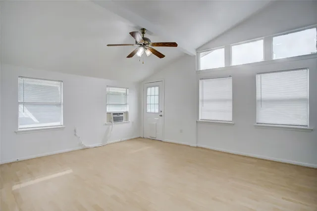 an empty room with windows and ceiling fan