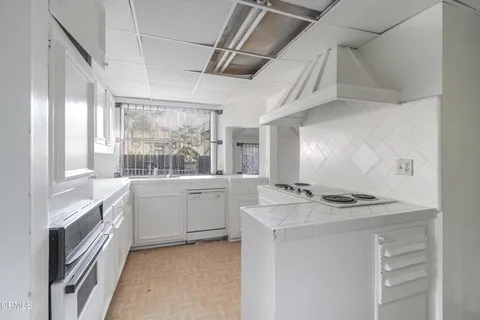 an empty room with wooden floor cabinet and windows