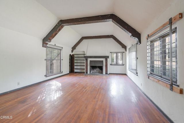 a view of empty room with wooden floor and fireplace